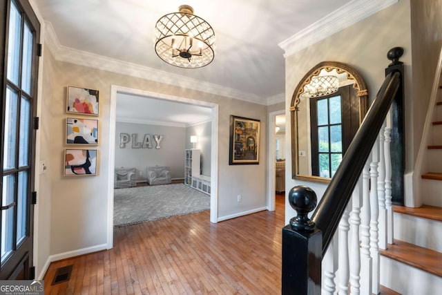 entryway featuring stairway, hardwood / wood-style flooring, baseboards, a chandelier, and crown molding