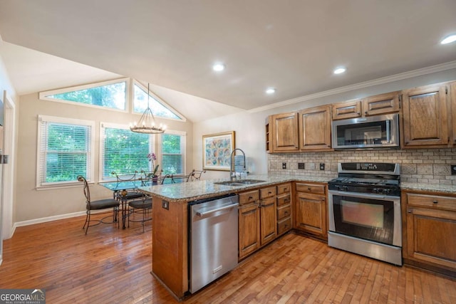 kitchen with stainless steel appliances, a sink, a peninsula, brown cabinets, and lofted ceiling