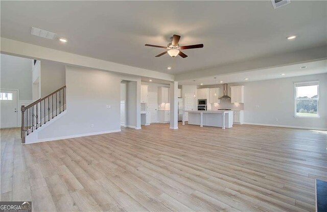 612 Sidney Ct, Stockbridge, GA 30281 - unfurnished living room featuring a ceiling fan, light wood-style flooring, baseboards, stairs, and recessed lighting