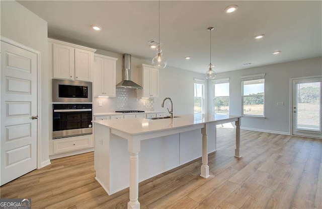 612 Sidney Ct, Stockbridge, GA 30281 - kitchen with stainless steel appliances, wall chimney range hood, a sink, an island with sink, and tasteful backsplash