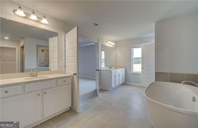 612 Sidney Ct, Stockbridge, GA 30281 - full bathroom with tile patterned floors, two vanities, a soaking tub, a shower stall, and baseboards