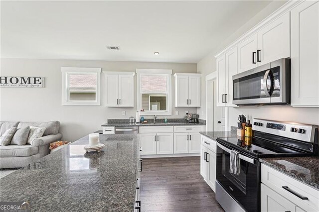 166 Wagon Trail Cir, Fairmount, GA 30139 - kitchen with appliances with stainless steel finishes, white cabinetry, open floor plan, dark stone countertops, and dark wood-style flooring