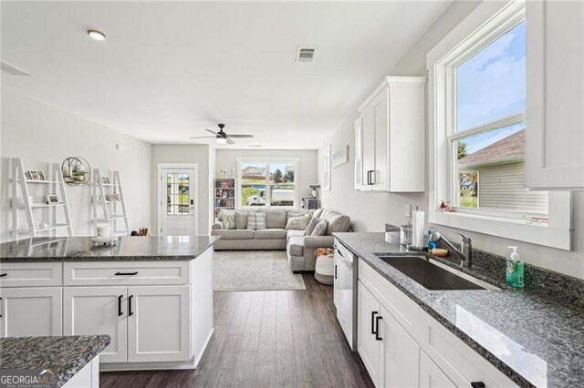 kitchen featuring a sink, dishwasher, ceiling fan, white cabinets, and dark stone countertops