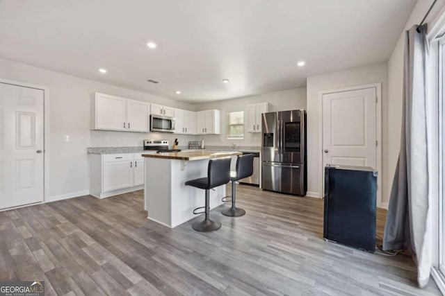 130 Maple Dr, Milner, GA 30257 - kitchen with appliances with stainless steel finishes, white cabinets, a breakfast bar area, a center island, and wood finished floors