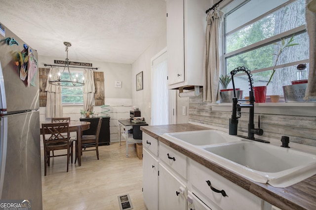 7 Valley View Dr, Cartersville, GA 30120 - kitchen with freestanding refrigerator, white cabinets, a chandelier, light wood finished floors, and a textured ceiling