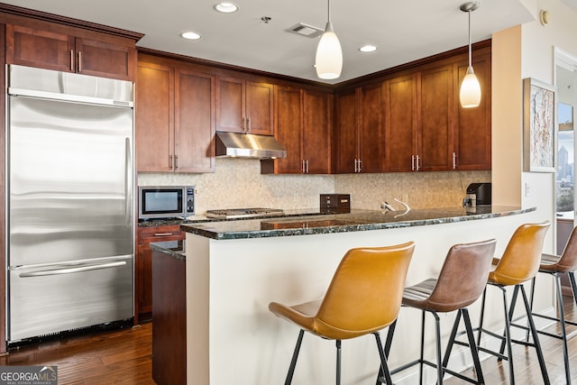 270 17th St NW Unit 1113, Atlanta, GA 30363 - kitchen featuring appliances with stainless steel finishes, under cabinet range hood, dark stone counters, a peninsula, and backsplash