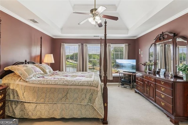 bedroom with a tray ceiling, light colored carpet, multiple windows, crown molding, and ceiling fan