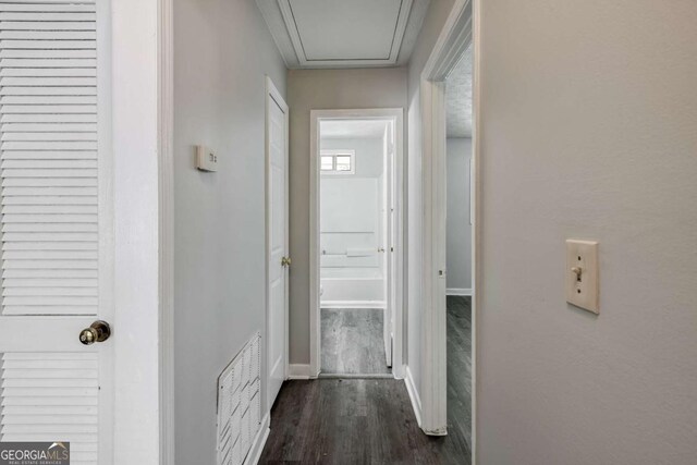 hallway featuring dark wood-style flooring and baseboards