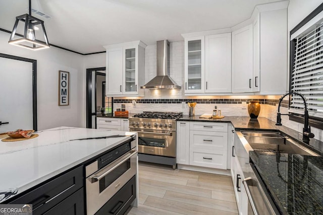 788 Sherwood Rd, Gainesville, GA 30501 - kitchen featuring wall chimney exhaust hood, appliances with stainless steel finishes, tasteful backsplash, a sink, and white cabinets