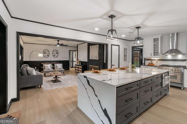 788 Sherwood Rd, Gainesville, GA 30501 - kitchen featuring wall chimney range hood, high end stove, white cabinets, tasteful backsplash, and recessed lighting