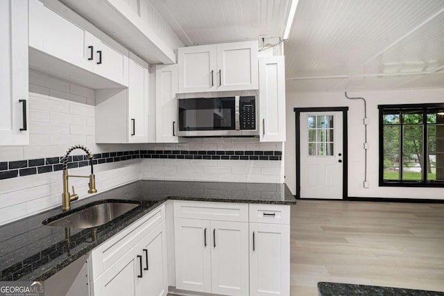 788 Sherwood Rd, Gainesville, GA 30501 - kitchen with stainless steel microwave, a sink, white cabinetry, backsplash, and dark stone counters