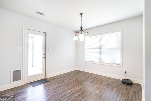 unfurnished dining area featuring a chandelier, dark wood finished floors, and baseboards