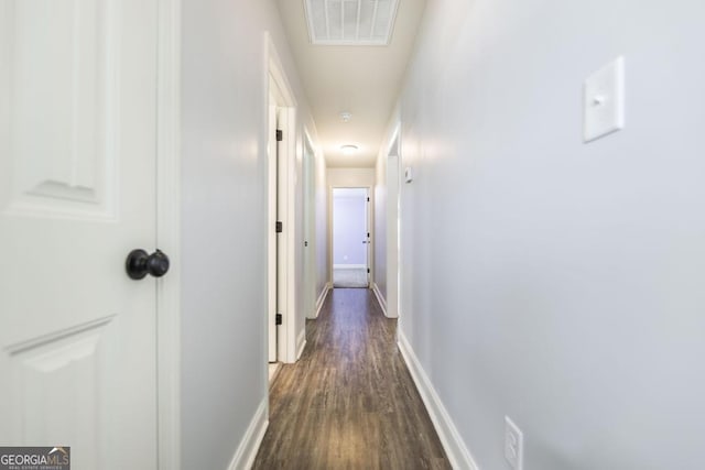hallway featuring dark wood-type flooring and baseboards