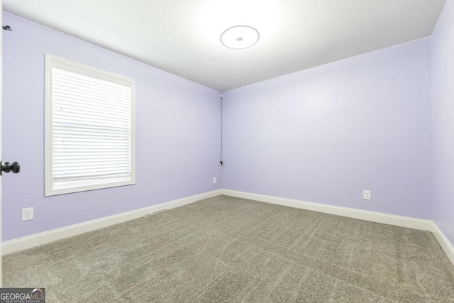 carpeted spare room featuring baseboards