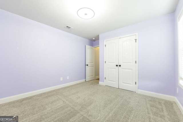 unfurnished bedroom with carpet flooring, baseboards, and a closet