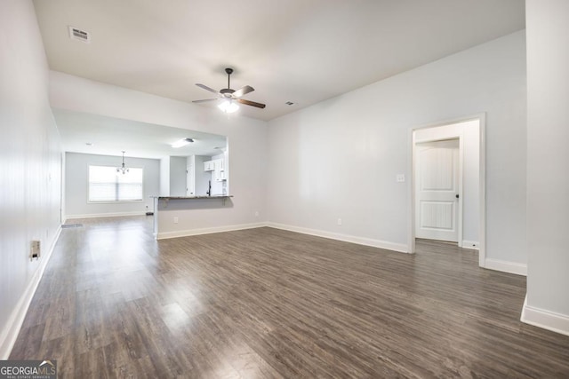 unfurnished living room with a ceiling fan, dark wood-style flooring, a chandelier, and baseboards