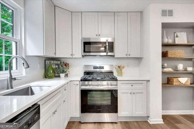 4368 Heritage Glen Ct, Marietta, GA 30068 - kitchen with stainless steel appliances, a sink, light wood-style flooring, light countertops, and white cabinets