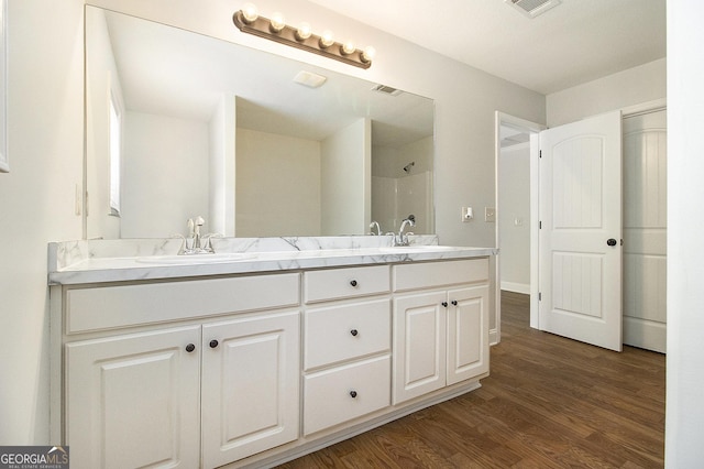 full bathroom with wood finished floors, a shower, and double vanity