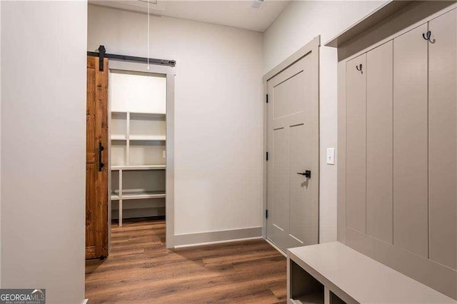 mudroom with dark wood-type flooring, baseboards, and a barn door