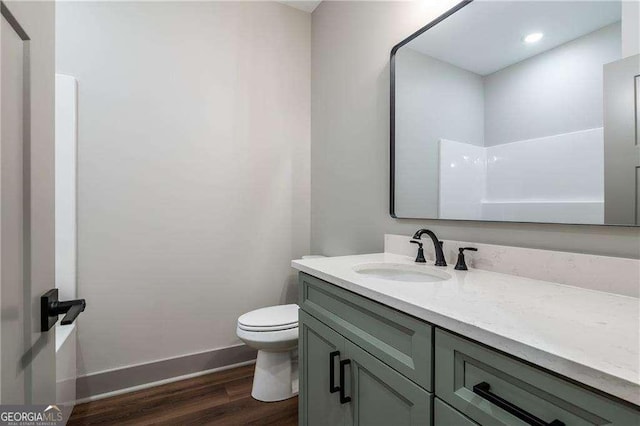 bathroom with wood finished floors, vanity, toilet, and baseboards