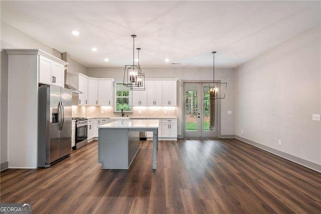 kitchen with appliances with stainless steel finishes, a chandelier, light countertops, tasteful backsplash, and a center island
