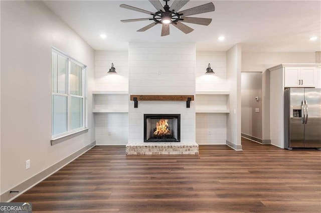 unfurnished living room with a ceiling fan, baseboards, a fireplace, dark wood finished floors, and recessed lighting
