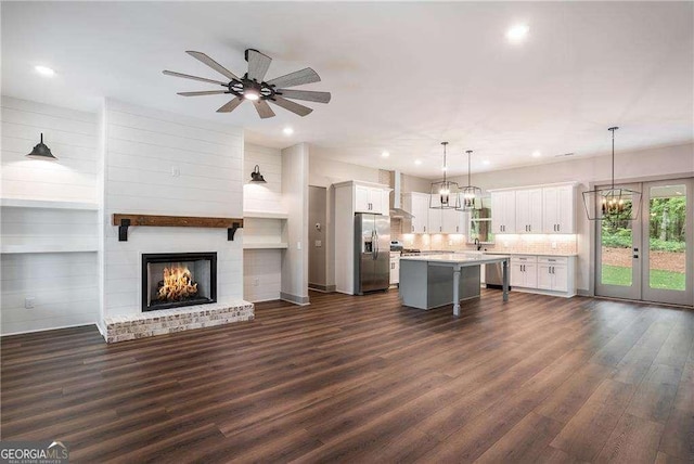 unfurnished living room with dark wood finished floors, recessed lighting, a ceiling fan, a brick fireplace, and a chandelier