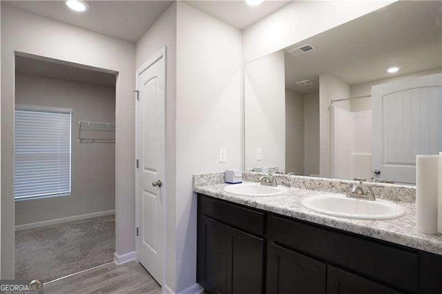 bathroom with wood finished floors, double vanity, and baseboards