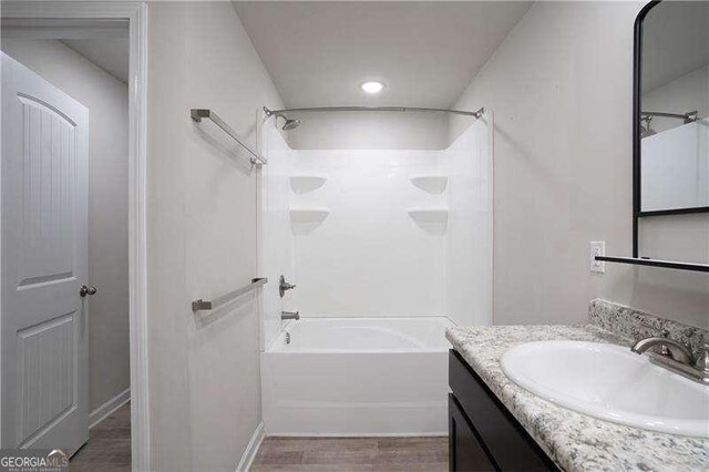 bathroom with tub / shower combination, vanity, recessed lighting, wood finished floors, and baseboards