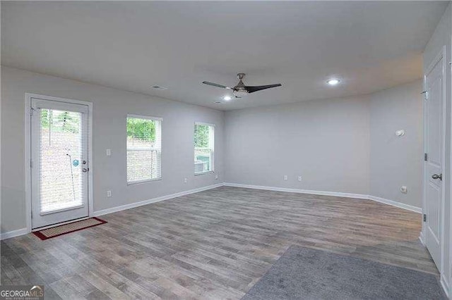 empty room with wood finished floors, ceiling fan, baseboards, and recessed lighting