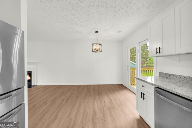 1645 Cobbs Creek Ln, Decatur, GA 30032 - kitchen with appliances with stainless steel finishes, light wood-style floors, a chandelier, white cabinetry, and light stone countertops