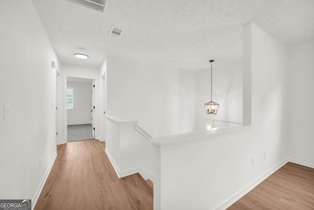 1645 Cobbs Creek Ln, Decatur, GA 30032 - hallway featuring an upstairs landing, wood finished floors, baseboards, a textured ceiling, and a chandelier
