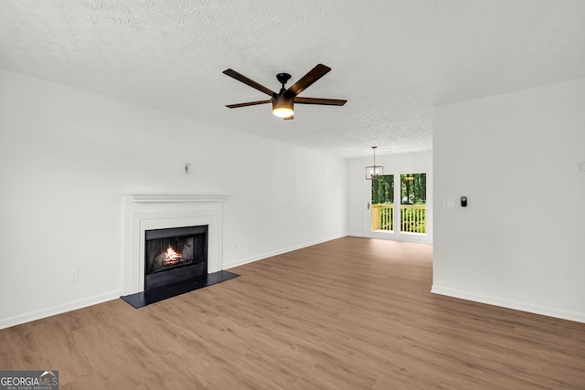 1645 Cobbs Creek Ln, Decatur, GA 30032 - unfurnished living room featuring wood finished floors, a warm lit fireplace, a textured ceiling, a ceiling fan, and a chandelier