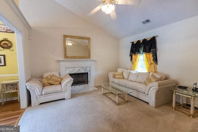 living room featuring ceiling fan, vaulted ceiling, and a high end fireplace