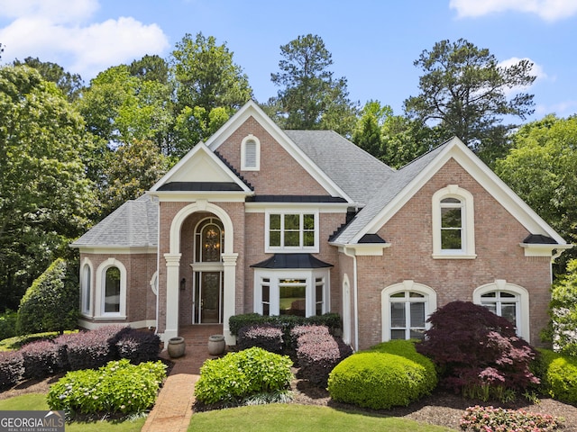 view of front of home featuring brick siding and a shingled roof