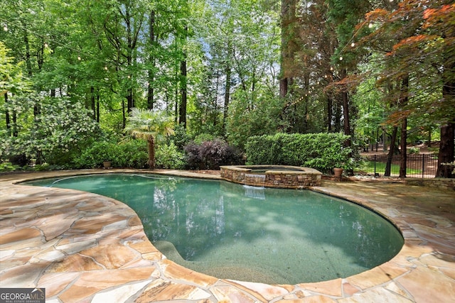 view of pool with fence, a patio area, and a pool with connected hot tub