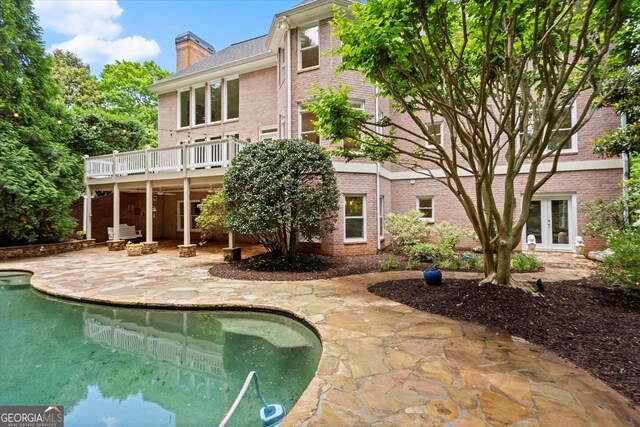 back of house featuring a patio, a chimney, brick siding, and an outdoor pool