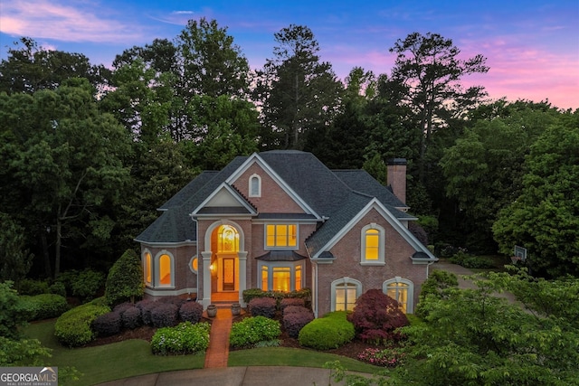 view of front of property featuring a chimney, brick siding, and a shingled roof