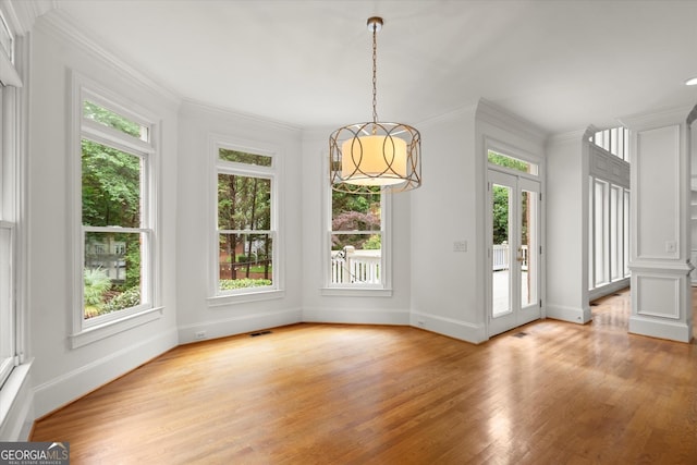 unfurnished dining area featuring healthy amount of natural light, light wood-style flooring, baseboards, and ornamental molding