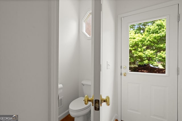 bathroom featuring healthy amount of natural light, toilet, and baseboards