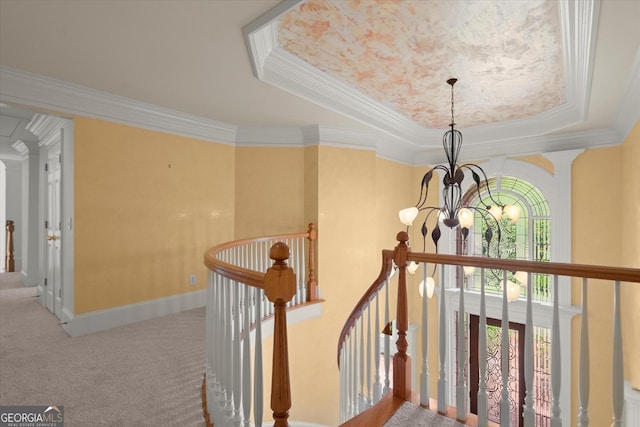 staircase featuring a chandelier, a tray ceiling, crown molding, and carpet