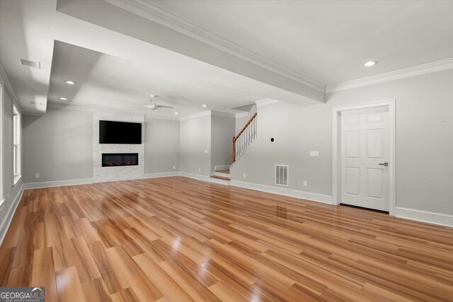 unfurnished living room with ceiling fan, crown molding, stairs, light wood-style flooring, and recessed lighting