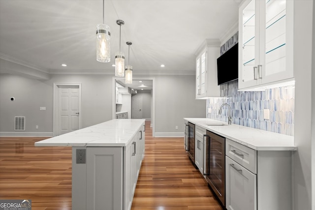 kitchen with a sink, baseboards, light wood finished floors, a center island, and recessed lighting