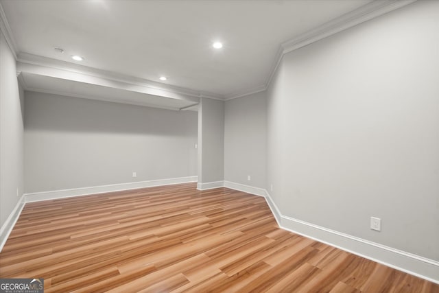 finished below grade area with crown molding, light wood finished floors, baseboards, and recessed lighting