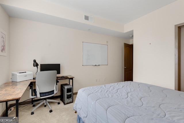 bedroom with light colored carpet and an office area