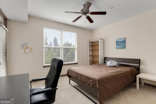bedroom featuring light colored carpet, baseboards, an office area, and a ceiling fan