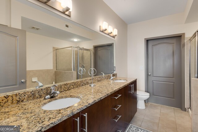 bathroom featuring a shower stall, tile patterned floors, double vanity, and toilet