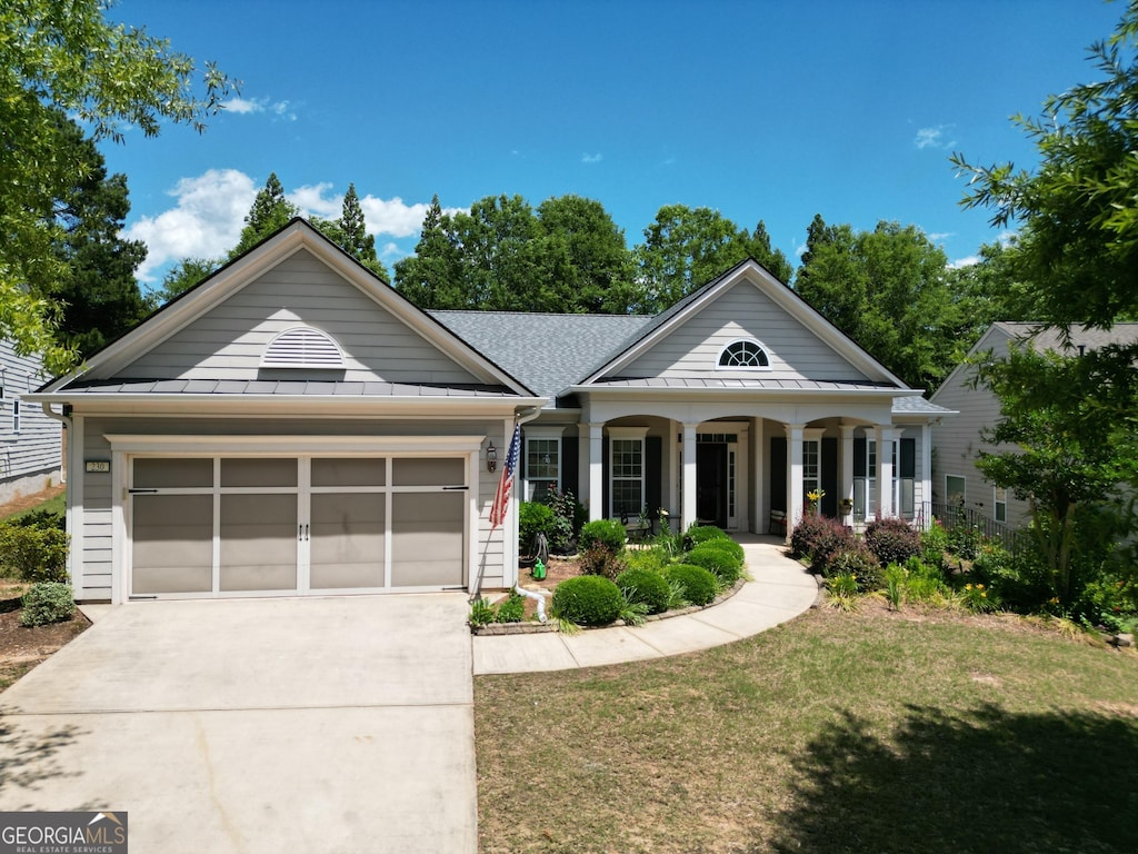 230 Begonia Ct, Griffin, GA 30223 - greek revival house featuring a standing seam roof, concrete driveway, an attached garage, covered porch, and a front lawn