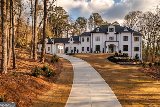 5211 Powers Ferry Rd, Sandy Springs, GA 30327 - french country style house featuring stucco siding and view of scattered trees