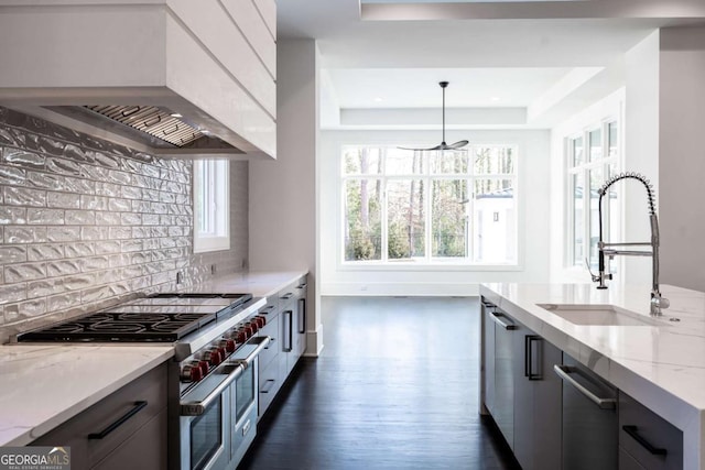 5211 Powers Ferry Rd, Sandy Springs, GA 30327 - kitchen featuring appliances with stainless steel finishes, a tray ceiling, wall chimney range hood, a sink, and light stone counters